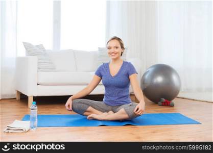 fitness, sport, people and healthy lifestyle concept - woman making yoga in lotus pose on mat