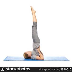 fitness, sport, people and healthy lifestyle concept - woman making yoga in shoulderstand pose on mat