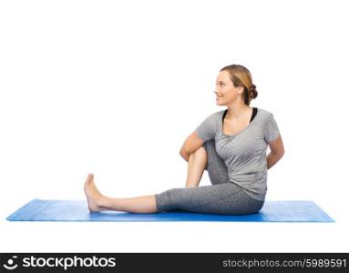 fitness, sport, people and healthy lifestyle concept - woman making yoga in twist pose on mat