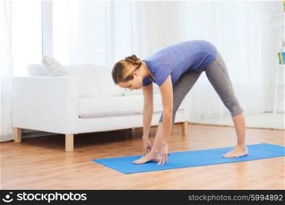 fitness, sport, people and healthy lifestyle concept - woman making yoga intense stretch pose on mat
