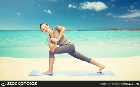 fitness, sport, people and healthy lifestyle concept - woman making yoga low angle lunge pose on mat over sea and sky background. woman making yoga low angle lunge pose on mat