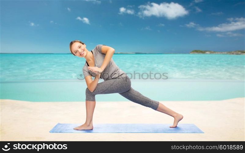 fitness, sport, people and healthy lifestyle concept - woman making yoga low angle lunge pose on mat over sea and sky background