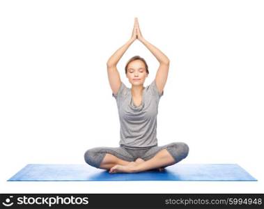 fitness, sport, people and healthy lifestyle concept - woman making yoga meditation in lotus pose on mat
