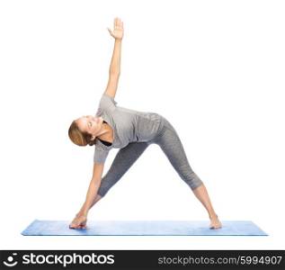 fitness, sport, people and healthy lifestyle concept - woman making yoga triangle pose on mat