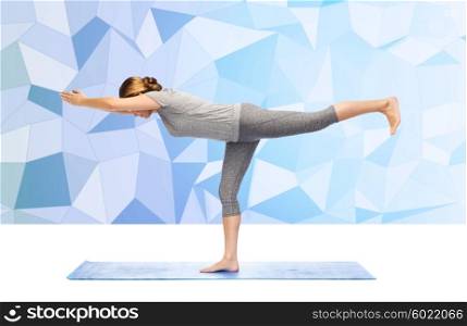 fitness, sport, people and healthy lifestyle concept - woman making yoga warrior pose on mat over low poly background