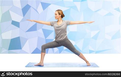 fitness, sport, people and healthy lifestyle concept - woman making yoga warrior pose on mat over blue polygonal background