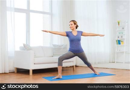 fitness, sport, people and healthy lifestyle concept - woman making yoga warrior pose on mat