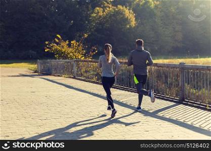 fitness, sport, people and jogging concept - couple running outdoors. couple running or jogging outdoors