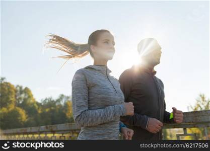 fitness, sport, people and jogging concept - happy couple running outdoors