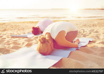 fitness, sport, people and lifestyle concept - close up of couple making yoga exercises on mats outdoors