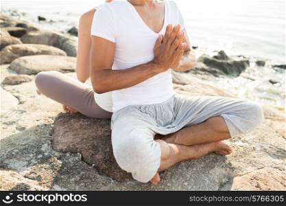 fitness, sport, people and lifestyle concept - close up of couple making yoga exercises sitting on pier outdoors