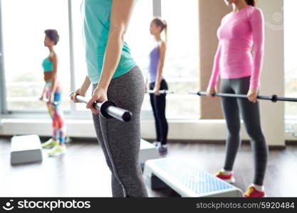 fitness, sport, people and lifestyle concept - close up of women exercising with bars and step platforms in gym