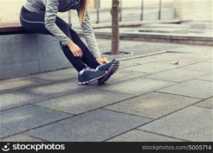 fitness, sport, people and lifestyle concept - close up of young sporty woman tying shoes outdoors. close up of sporty woman tying shoes outdoors