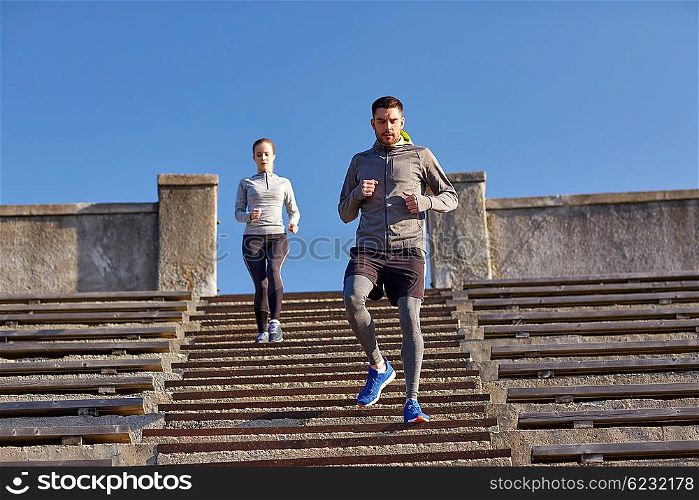 fitness, sport, people and lifestyle concept - couple running downstairs in city