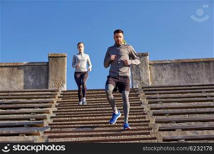 fitness, sport, people and lifestyle concept - couple running downstairs in city
