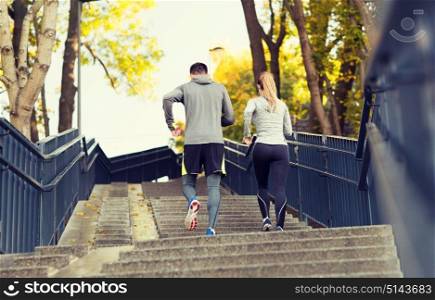 fitness, sport, people and lifestyle concept - couple running upstairs in city park. couple running upstairs in city park