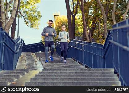 fitness, sport, people and lifestyle concept - happy couple running downstairs in city. happy couple running downstairs in city
