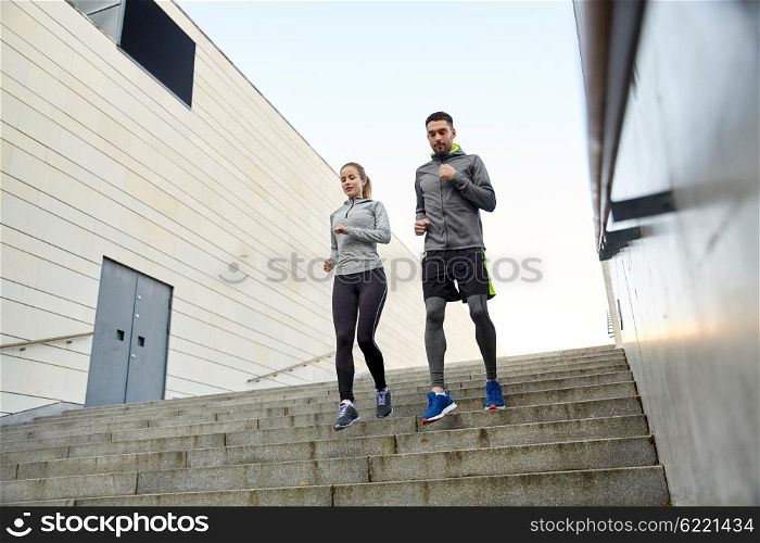 fitness, sport, people and lifestyle concept - happy couple running downstairs in city