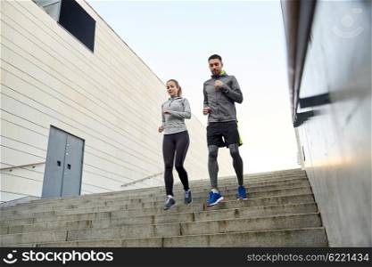 fitness, sport, people and lifestyle concept - happy couple running downstairs in city