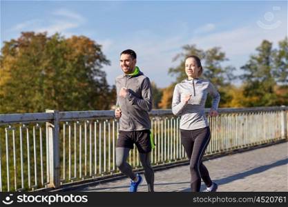 fitness, sport, people and lifestyle concept - happy couple running outdoors