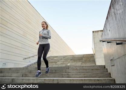 fitness, sport, people and lifestyle concept - happy sporty woman running downstairs in city