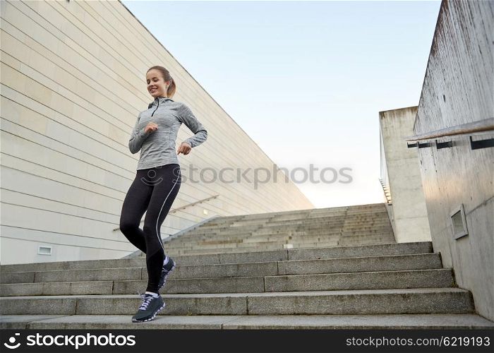 fitness, sport, people and lifestyle concept - happy sporty woman running downstairs in city