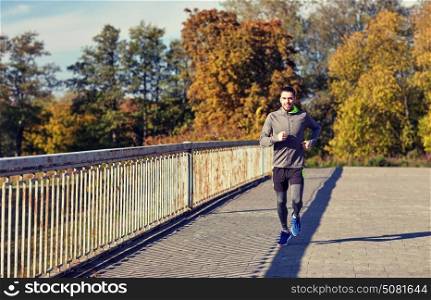 fitness, sport, people and lifestyle concept - happy young man running over city bridge. happy young man running over city bridge