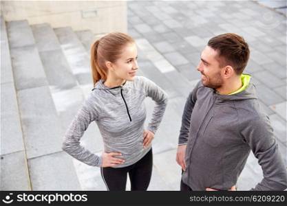 fitness, sport, people and lifestyle concept - smiling couple outdoors on city street