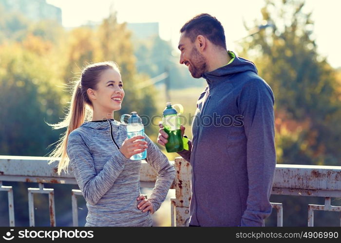 fitness, sport, people and lifestyle concept - smiling couple with bottles of water outdoors. smiling couple with bottles of water outdoors