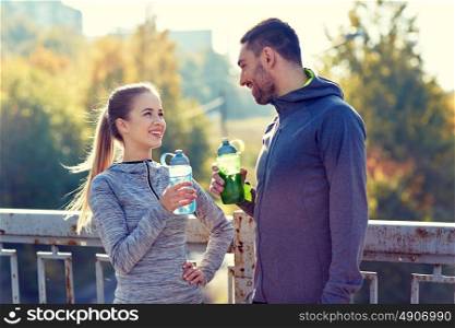 fitness, sport, people and lifestyle concept - smiling couple with bottles of water outdoors. smiling couple with bottles of water outdoors
