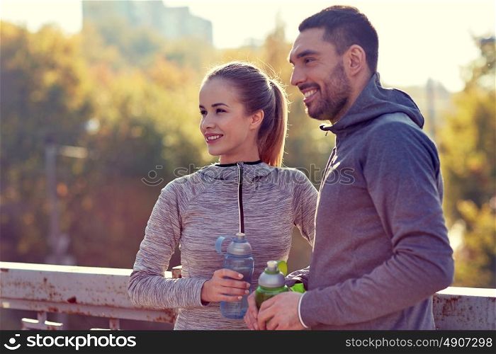 fitness, sport, people and lifestyle concept - smiling couple with bottles of water outdoors. smiling couple with bottles of water outdoors
