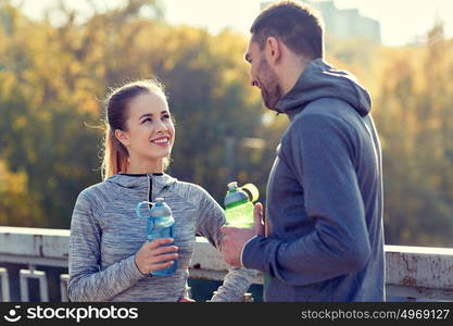 fitness, sport, people and lifestyle concept - smiling couple with bottles of water outdoors. smiling couple with bottles of water outdoors