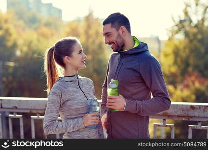 fitness, sport, people and lifestyle concept - smiling couple with bottles of water outdoors. smiling couple with bottles of water outdoors. smiling couple with bottles of water outdoors