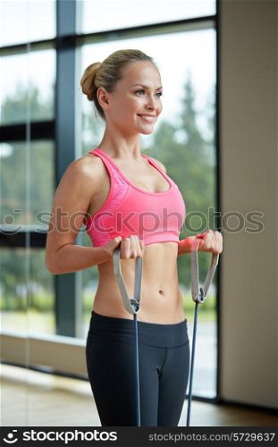 fitness, sport, people and lifestyle concept - smiling woman doing exercises with expander in gym