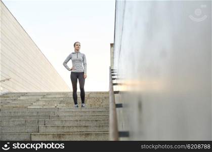 fitness, sport, people and lifestyle concept - sporty woman standing on in city stairs