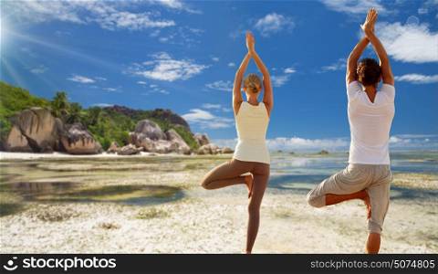fitness, sport, people and recreation concept - young woman making yoga in tree pose from back over exotic tropical beach background. young woman making yoga tree pose outdoors