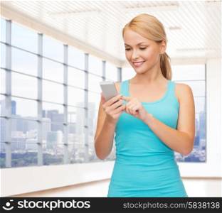 fitness, sport, people and technology concept - smiling woman with smartphone over gym or home background