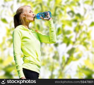fitness, sport, people and thirst concept - happy woman drinking bottle water after doing sports over green tree leaves background