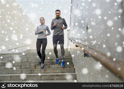 fitness, sport, people, exercising and healthy lifestyle concept - couple of sportsmen running downstairs outdoors over snow