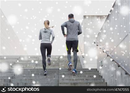 fitness, sport, people, exercising and healthy lifestyle concept - couple of sportsmen running upstairs outdoors over snow