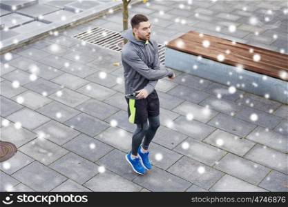 fitness, sport, people, exercising and healthy lifestyle concept - man skipping with jump rope outdoors over snow