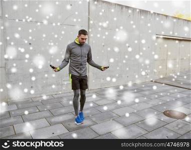 fitness, sport, people, exercising and healthy lifestyle concept - man skipping with jump rope outdoors over snow