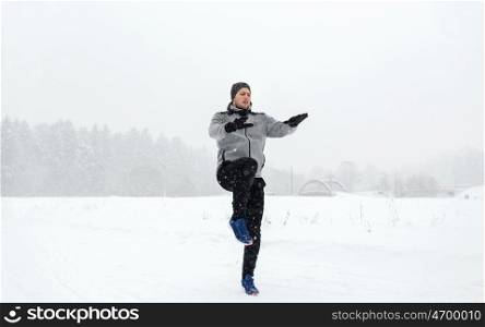 fitness, sport, people, exercising and healthy lifestyle concept - young man exercising and warmig up in winter outdoors