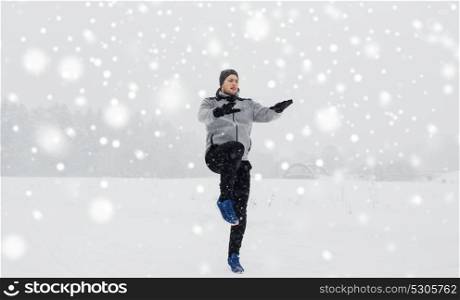 fitness, sport, people, exercising and healthy lifestyle concept - young man exercising and warmig up in winter outdoors. man exercising and warmig up in winter outdoors