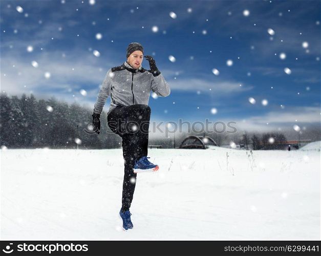 fitness, sport, people, exercising and healthy lifestyle concept - young man exercising and warmig up in winter outdoors. man exercising and warmig up in winter outdoors