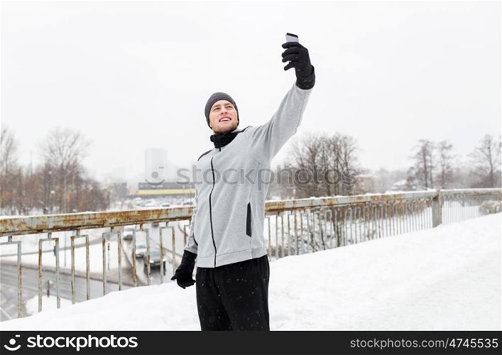 fitness, sport, people, exercising and healthy lifestyle concept - young man taking selfie with smartphone in winter