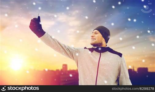 fitness, sport, people, exercising and healthy lifestyle concept - young man taking selfie with smartphone in winter . man taking selfie with smartphone in winter