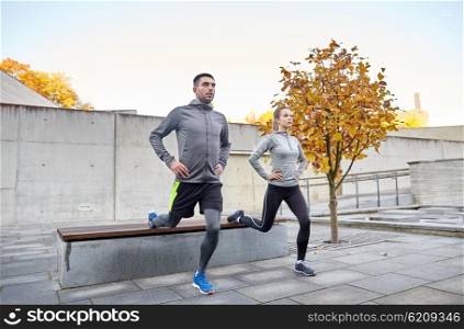fitness, sport, people, exercising and lifestyle concept - couple doing lunge exercise on city street