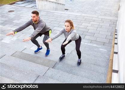 fitness, sport, people, exercising and lifestyle concept - couple doing squats on city street stairs