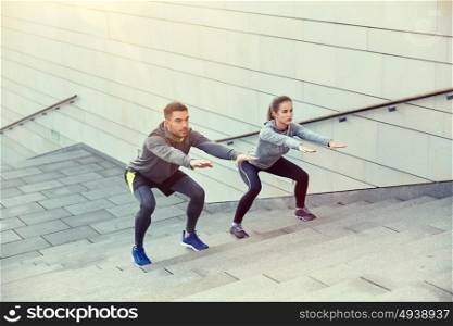 fitness, sport, people, exercising and lifestyle concept - couple doing squats on city street stairs. couple doing squats on city street stairs